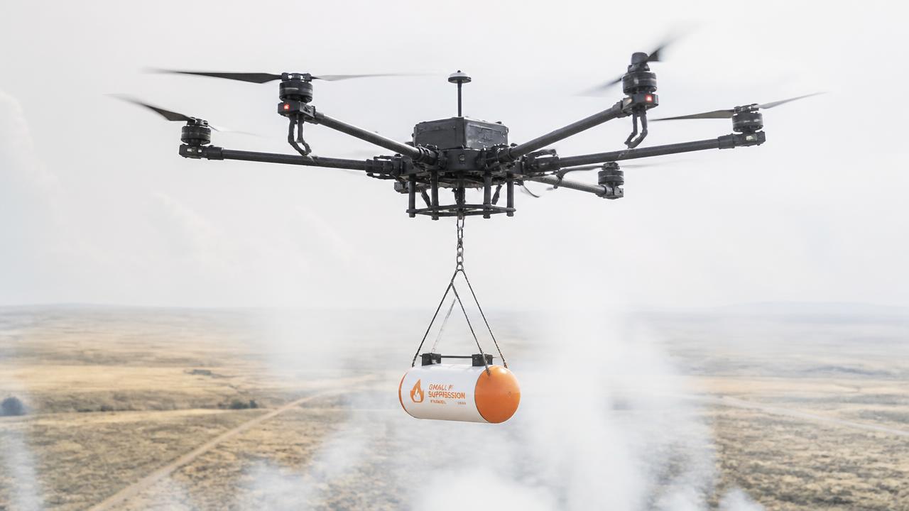 Drone carrying a QuenchPod capsule above dry grassland